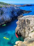 Vista sulla cala Tonda e la nostra istuttrice di kayak che si prepara a saltare dalla roccia
